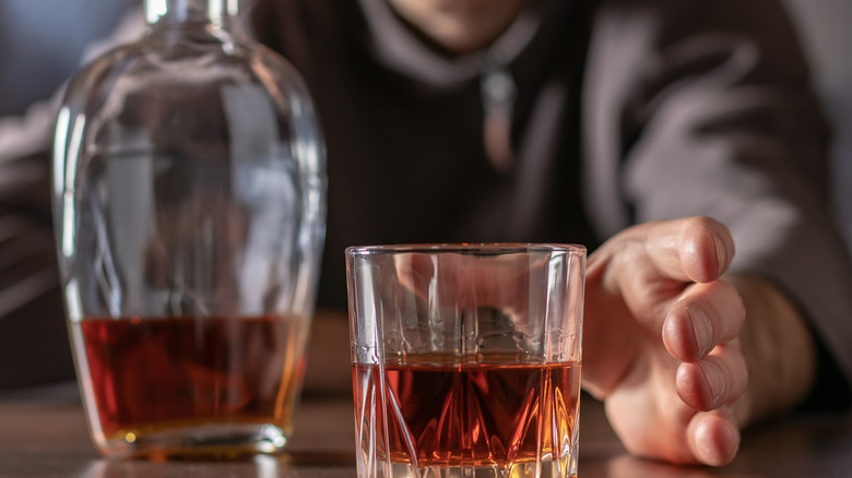 male pulls his hand to an alcoholic drink