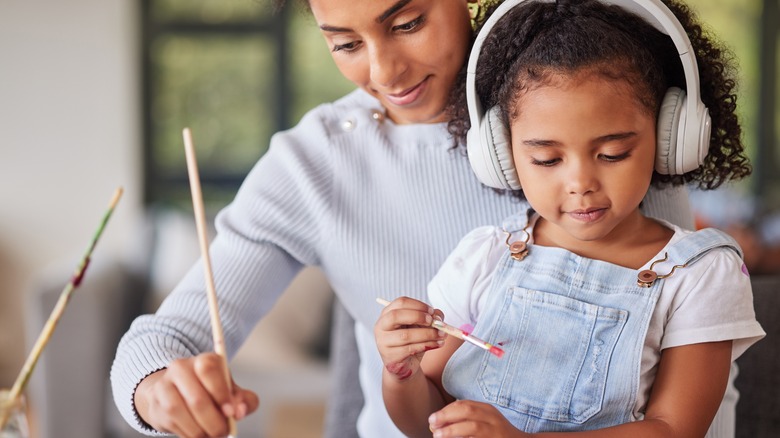 Young girl painting wearing headphones