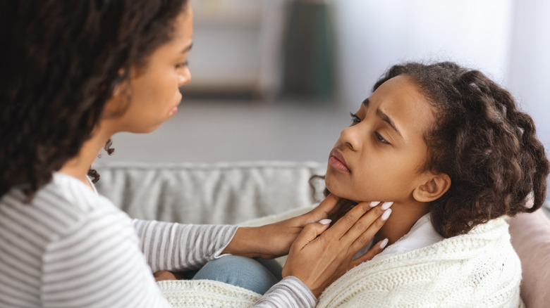 Mom touching sick child's throat