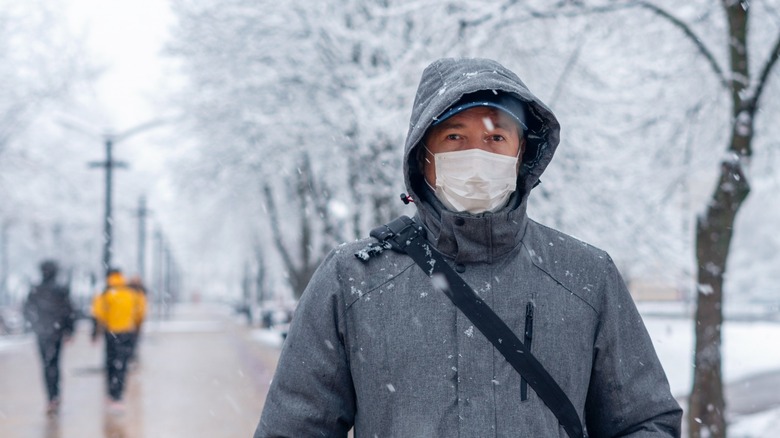 man in snow wears mask 