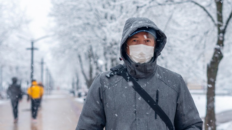 man in snow wears mask 