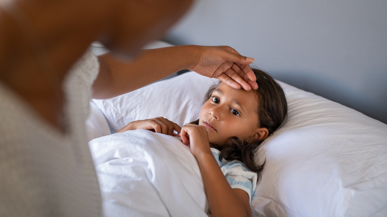 Mom checking temperature of sick daughter