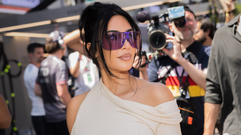 Kim Kardashian wearing a beige dress with purple sunglasses