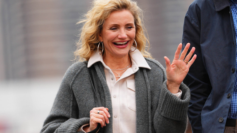 Cameron Diaz waving and laughing as she walks down the street