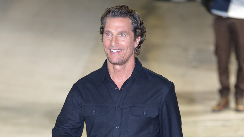 Matthew McCounaughey walking down the street in a button-up shirt and casual pants