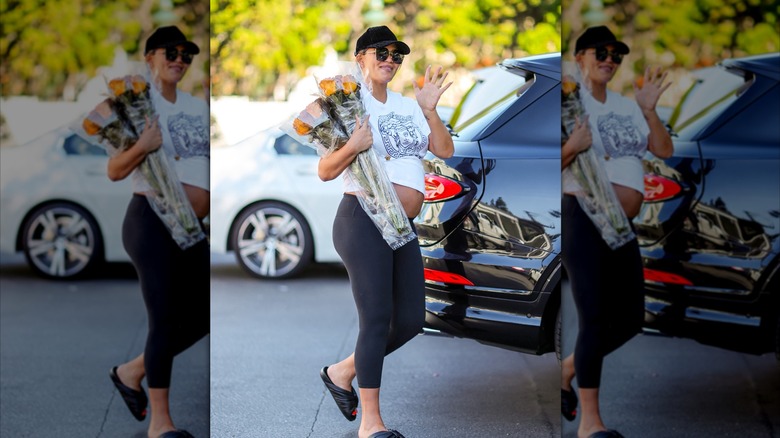 Chrissy Teigen walking and carrying flowers