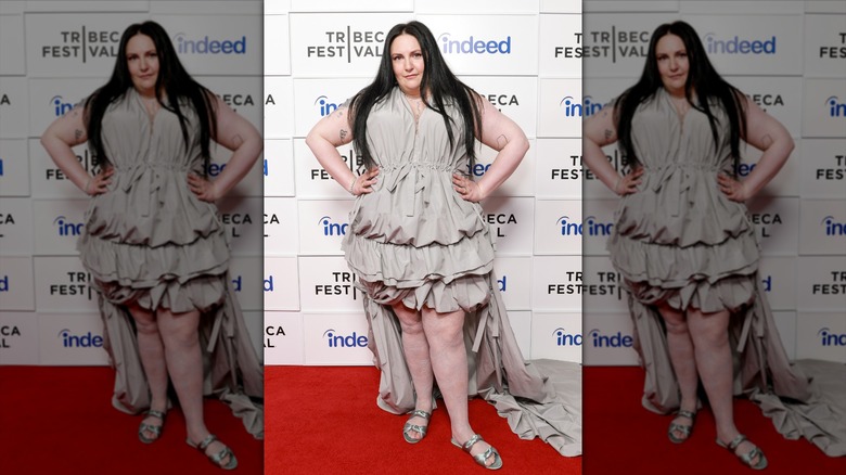 Lena Dunham posing during a celebrity event while wearing a champagne colored gown