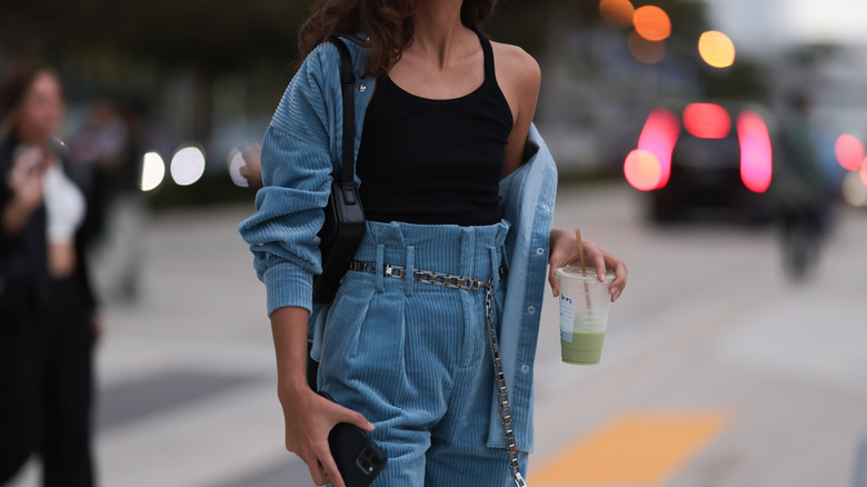 Close up of midsection of a woman in a matching blue set, holding a matcha.