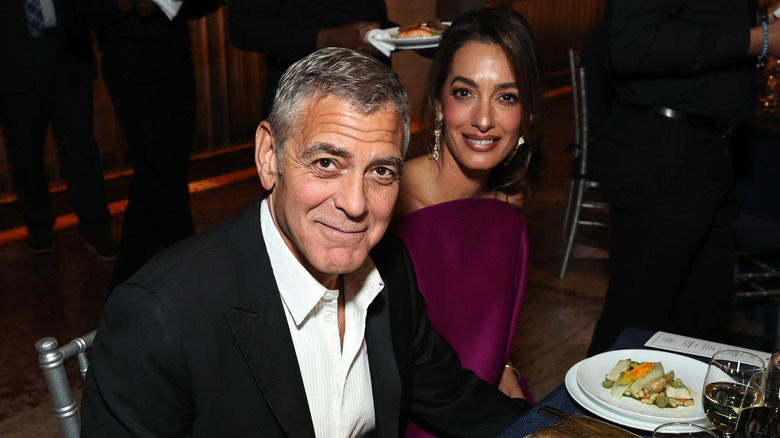 George and Amal Clooney eating during a gala publicity event