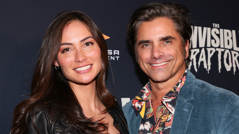 John Stamos and Caitlin McHugh smiling at an event