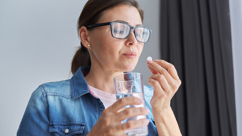 woman wearing glasses holding pill
