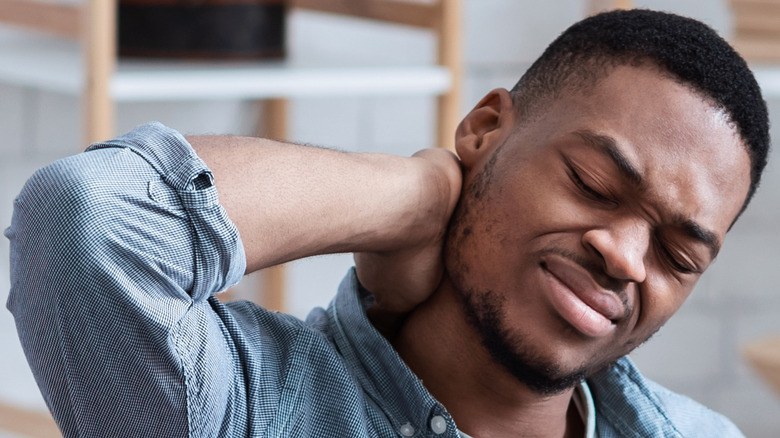 Man holding neck with painful face