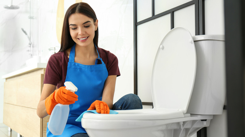 Smiling woman cleaning toilet