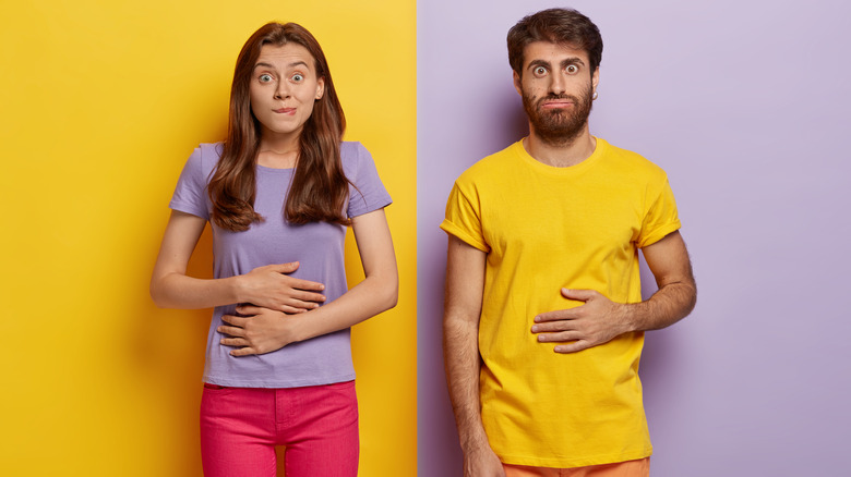 Man and woman holding stomachs