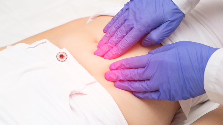 A doctor pressing on a woman's abdomen