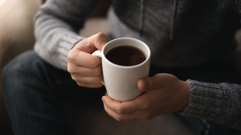 Hands holding full coffee mug