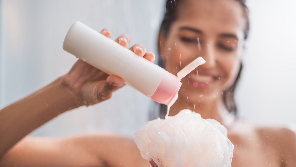 A woman adds soap to a shower pouf