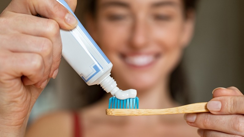 woman putting toothpaste on toothbrush