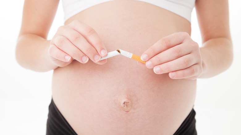 pregnant woman breaking cigarette