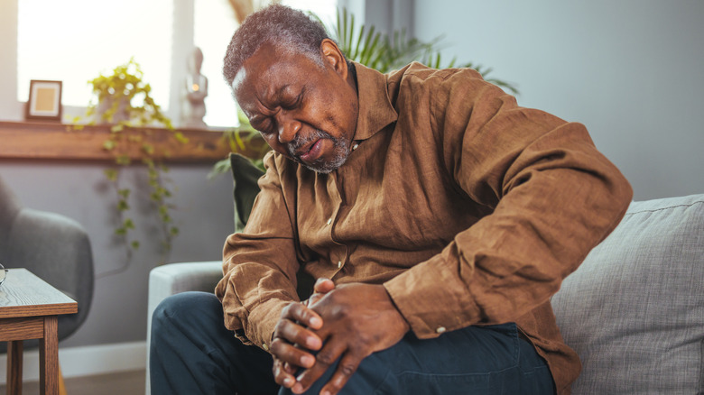 Wincing older man holding knee