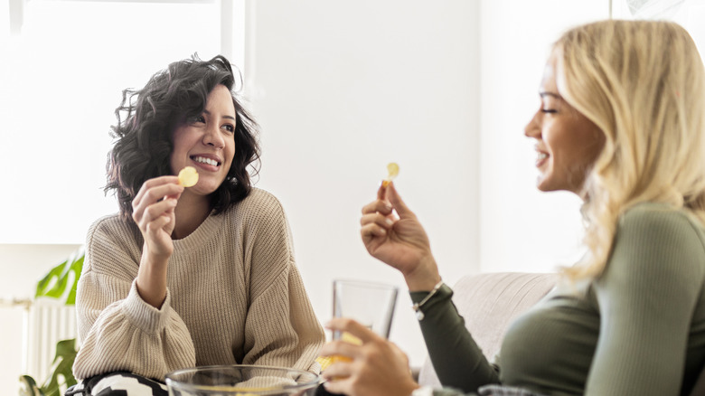 two women talking and eating potato chips
