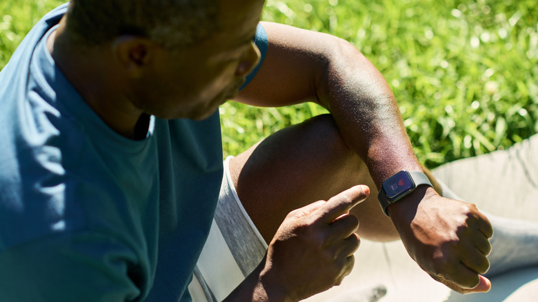 young man checking health app on his smartwatch