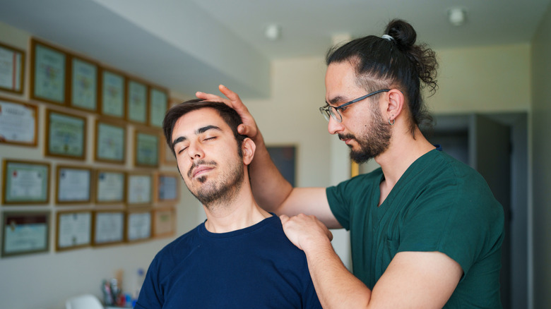 young male alternative medicine practitioner works on young male patient
