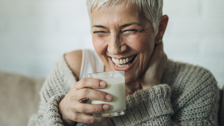 older woman smiling while drinking milk