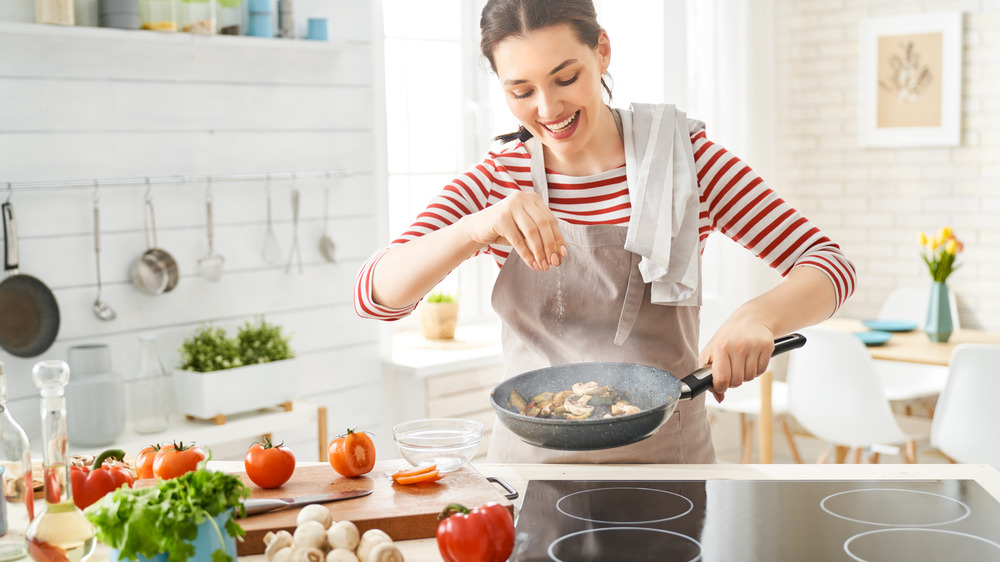 woman adding food to a frying pan