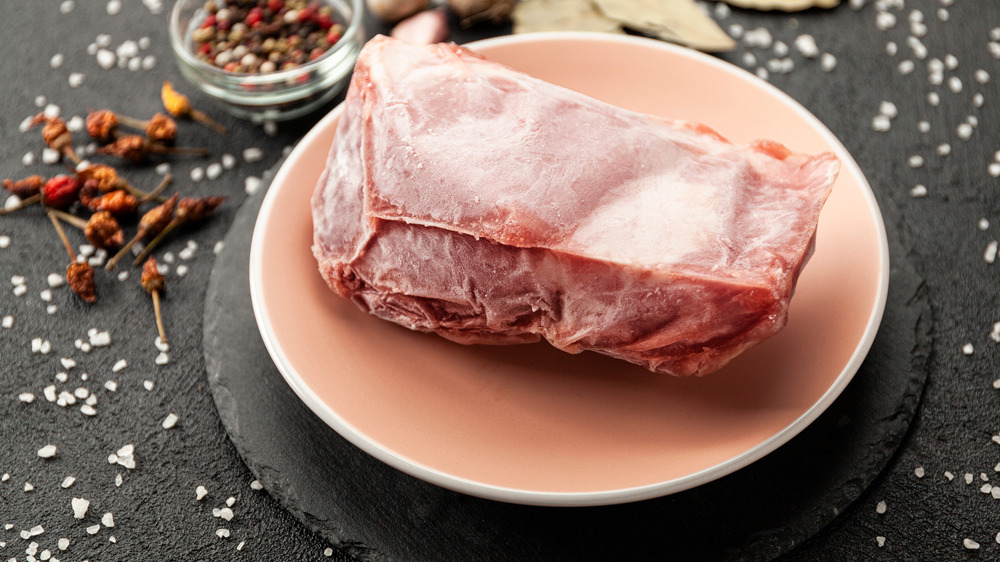 frozen meat thawing on plate on table