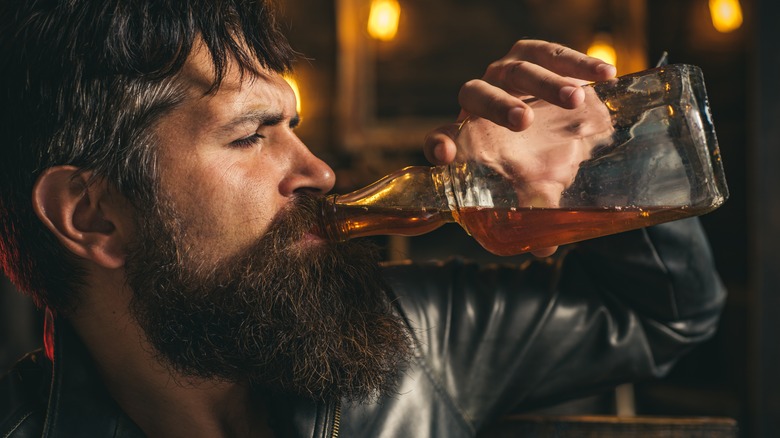 bearded man drinking liquor bottle