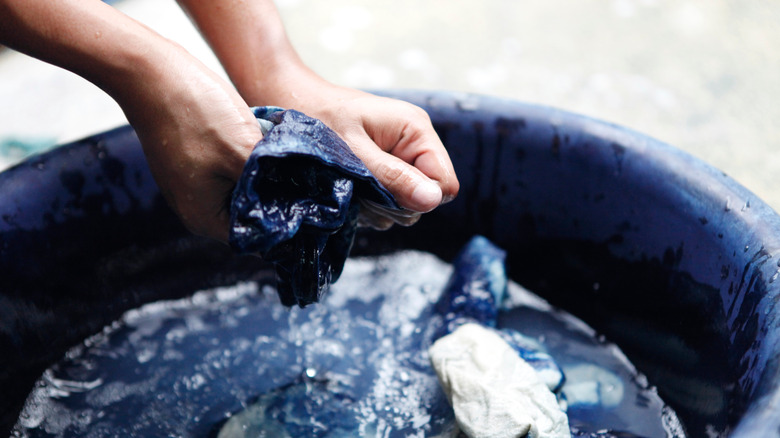 hands squeezing fabric soaked in dye 