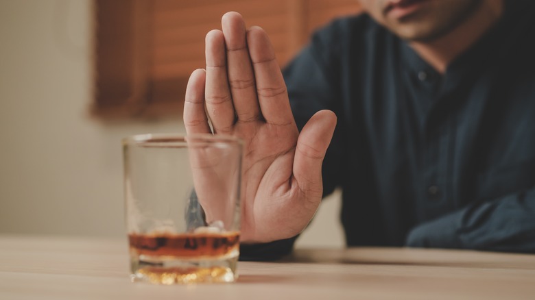 man's hand pushing away alcohol glass