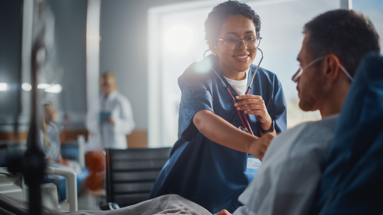 Hispanic woman doctor listening to man's lungs