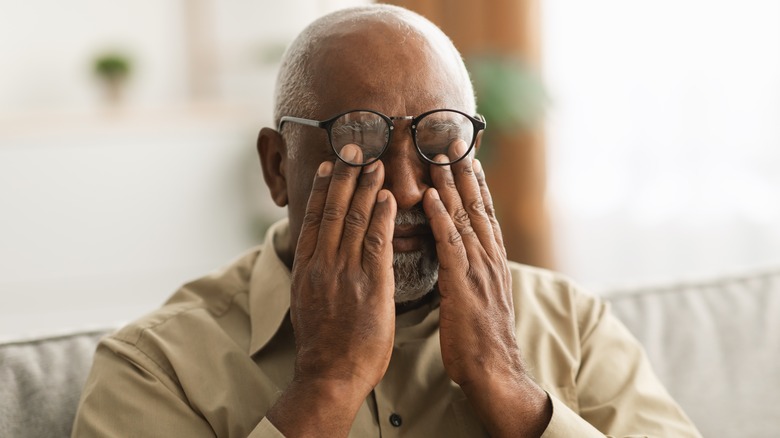 Older man wearing glasses rubbing his eyes