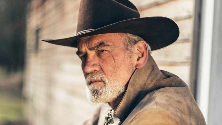 A pensive senior cowboy staring at a faraway object