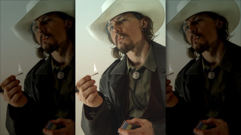 A cowboy holding a lit match