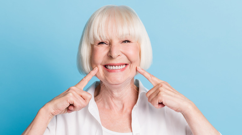 senior woman smiling and pointing at teeth