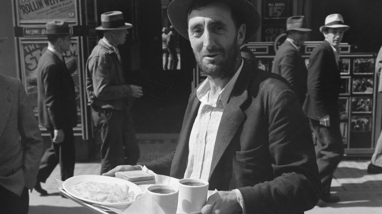 A man carrying a tray of food during the Depression Era