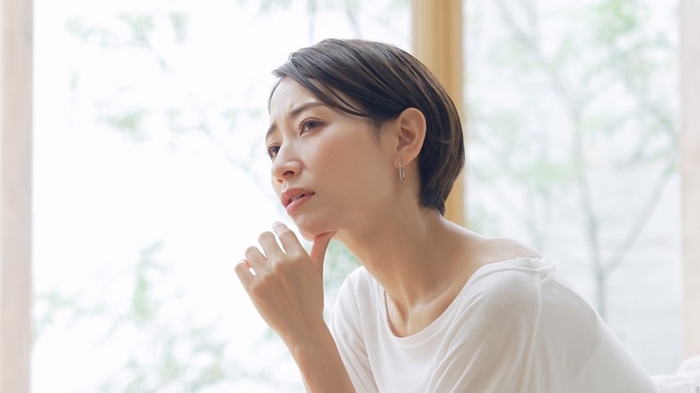 woman looking pensively next to a window