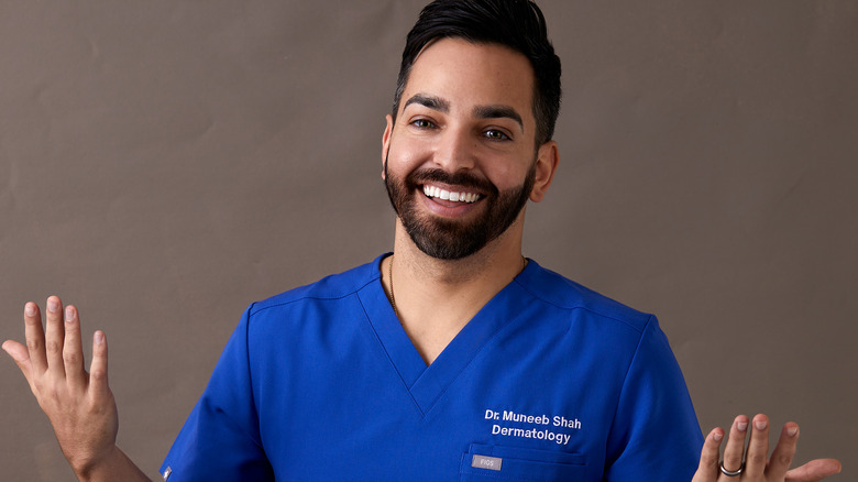 Dr. Muneeb Shah in blue scrubs shrugging