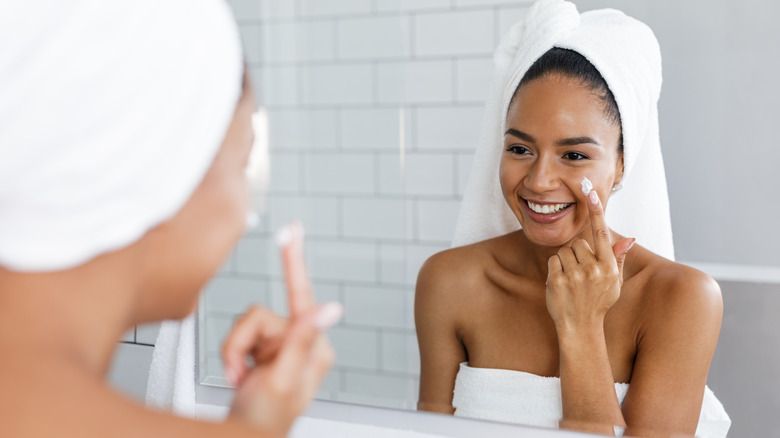 Smiling woman applying face cream