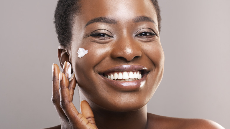 Smiling woman dabbing on facial cream