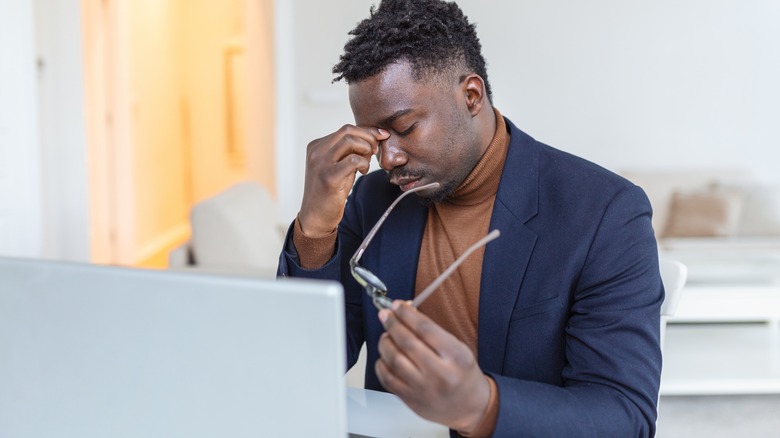 Man with eye strain at his laptop