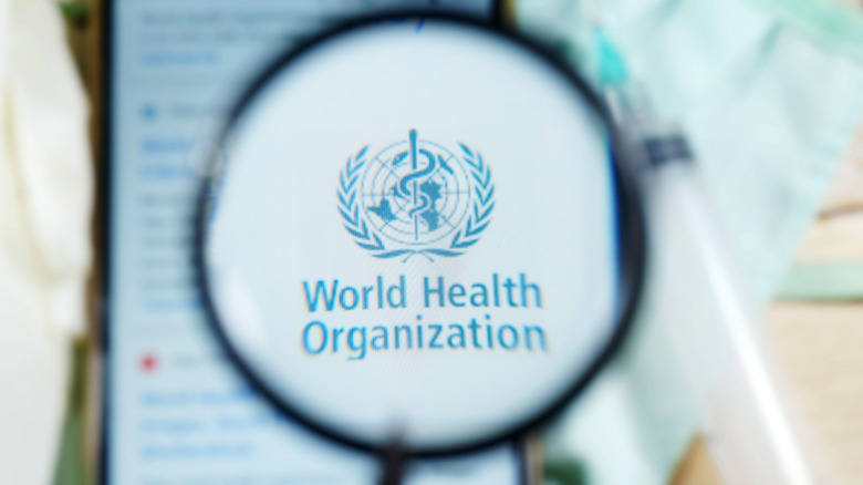 WHO (World Health Organization) logo under magnifying glass