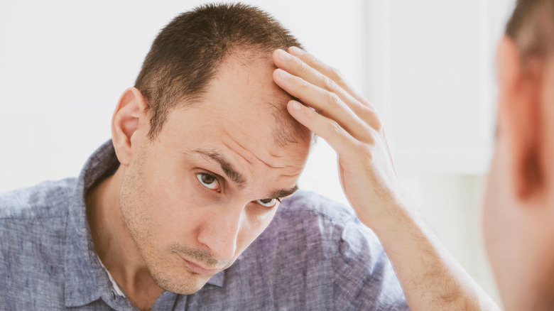 Man looking at receding hair in the mirror