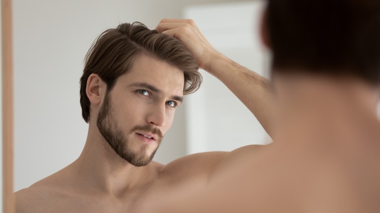 Man looking in the mirror considering hair loss treatment