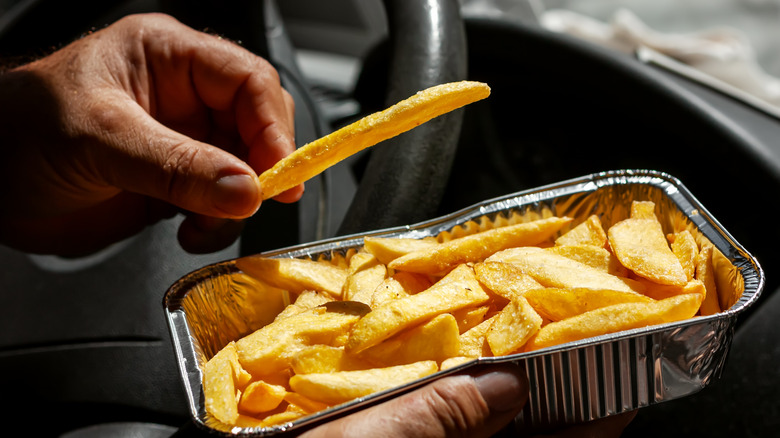 man's hands holding tray of french fries