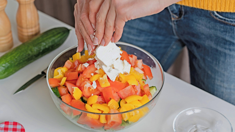 woman putting feta cheese on a salad