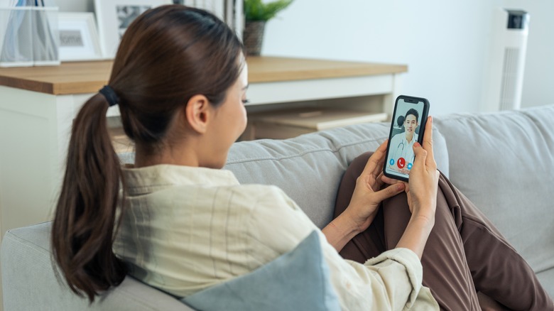 Woman on the couch talking to a doctor on a cell phone